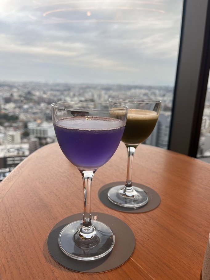 茶色のテーブルに置いてある紫と茶色の２つのカクテルの写真